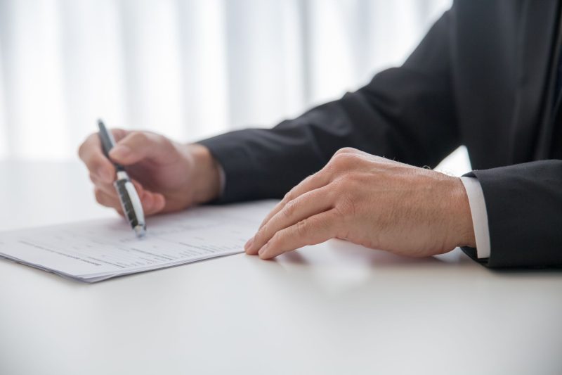 Home 9 Businessman signing important documents at office desk 1785258602